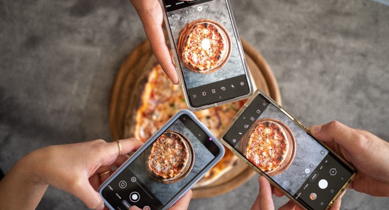 Phones taking picures of pizza